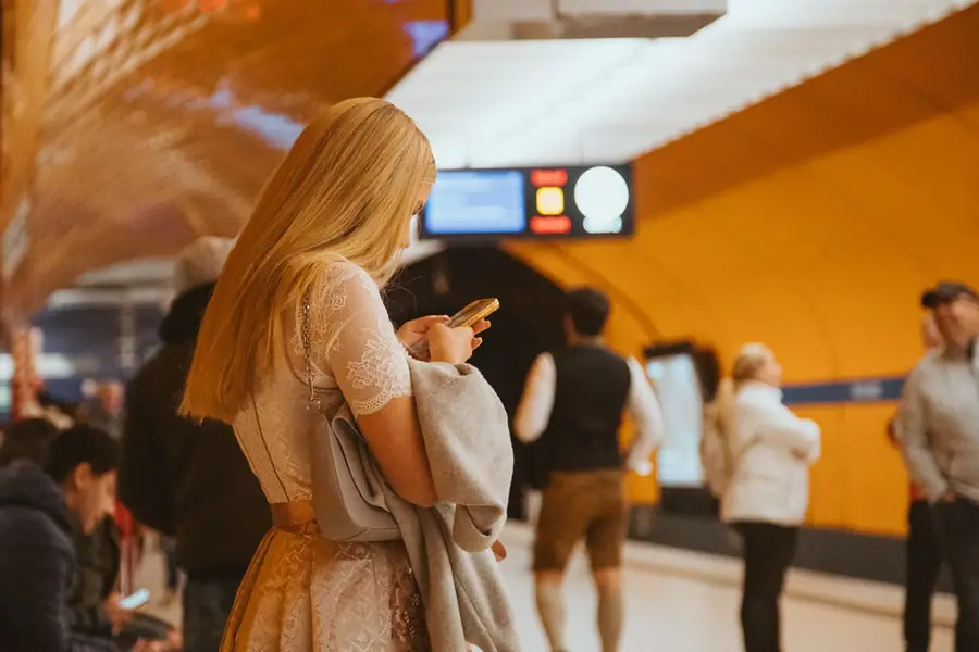 Jovem usando o smartphone em uma estação de metrô em Munique Jovem usando o smartphone em uma estação de metrô em Munique