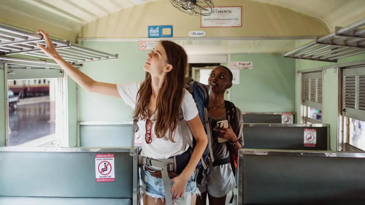 Duas mochileiras dentro de um vagão de trem ajeitando a bagagem