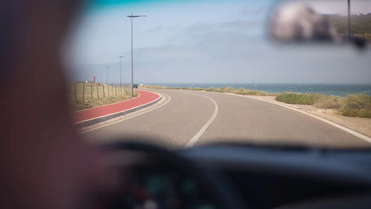 Vista pelo para-brisa de uma estrada costeira em Portugal em um dia de sol