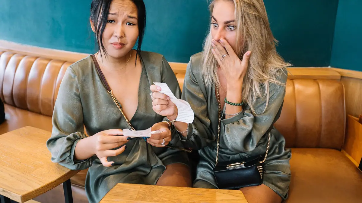 Duas mulheres surpresas olhando a conta de um restaurante