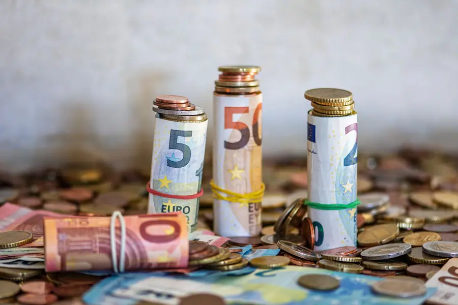 Cédulas de euro enroladas e moedas sobre uma mesa