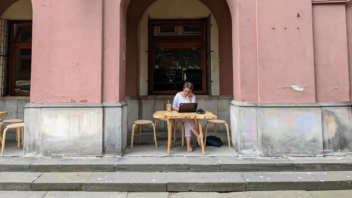 Mulher trabalhando em um notebook em uma mesa externa de café na Europa