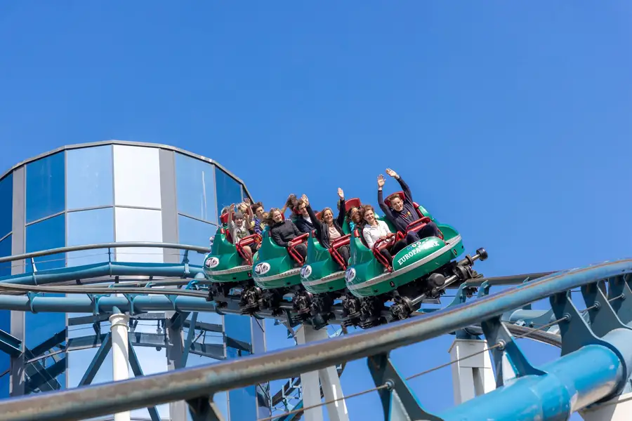 Pessoas se divertindo em uma montanha-russa no Europa-Park sob um céu azul Pessoas se divertindo em uma montanha-russa no Europa-Park sob um céu azul