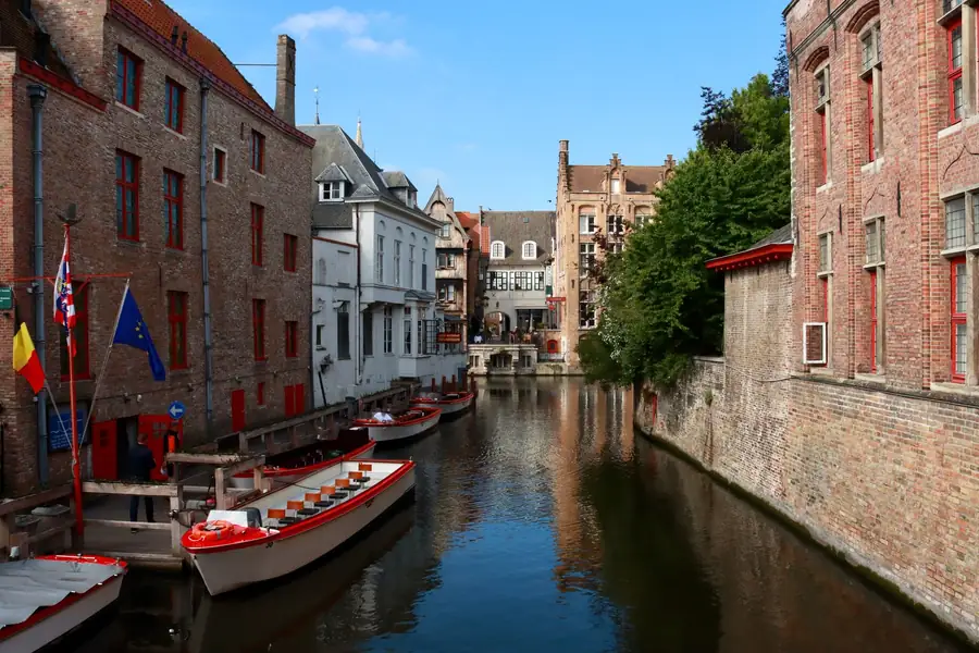Canal de Bruges com barcos atracados e prédios históricos Canal de Bruges com barcos atracados e prédios históricos