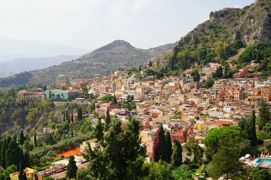 Vista aérea de Taormina, na Sicília, com construções coloridas e vegetação Vista aérea de Taormina, na Sicília, com construções coloridas e vegetação