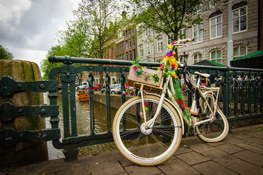 Pessoas passeando de bicicleta ao lado de um canal em Amsterdã