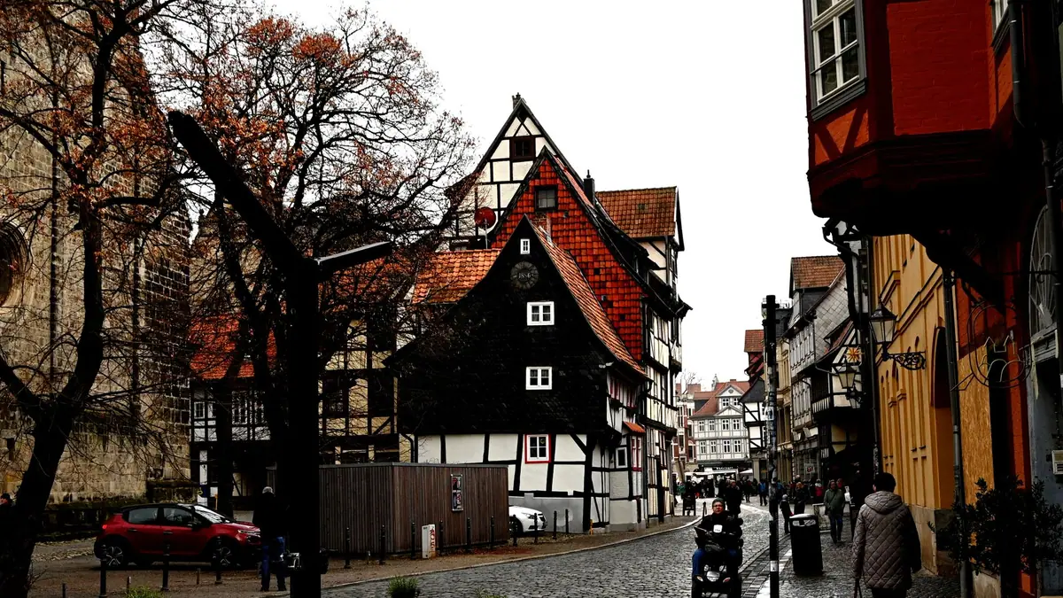 Ruas históricas de uma cidade europeia com casas de enxaimel e pessoas passeando