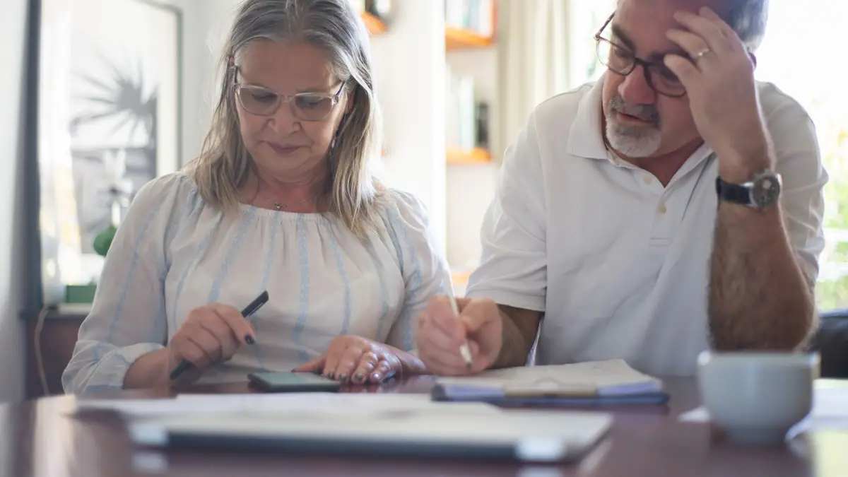 Casal de idosos organizando as finanças e analisando um orçamento na sala de casa
