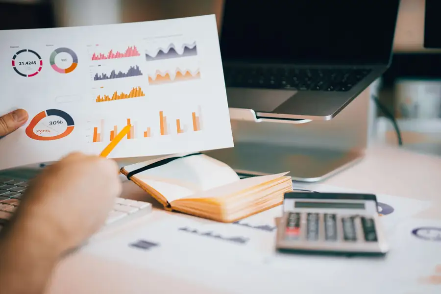 Mãos analisando dados financeiros com gráficos, notebook e calculadora Mãos analisando dados financeiros com gráficos, notebook e calculadora
