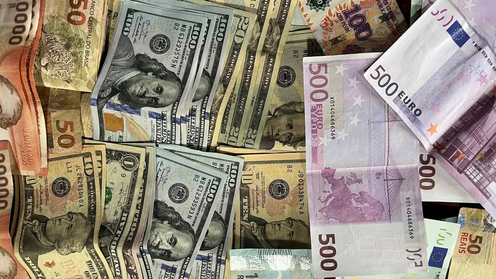 Notas de várias moedas internacionais organizadas sobre uma mesa
