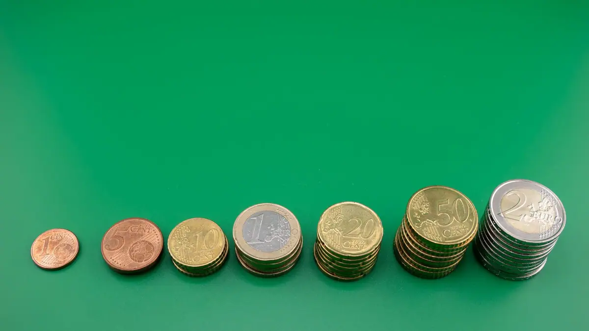 Moedas de euro empilhadas em colunas de alturas crescentes sobre fundo verde