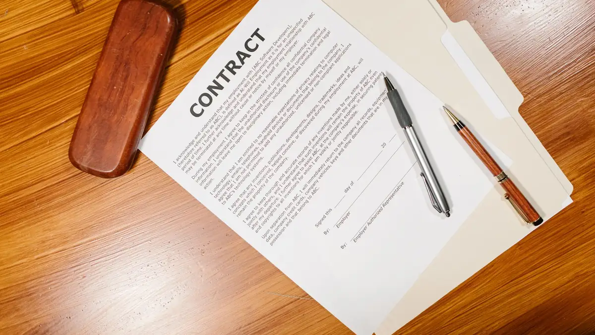 Contrato com canetas sobre uma mesa de madeira
