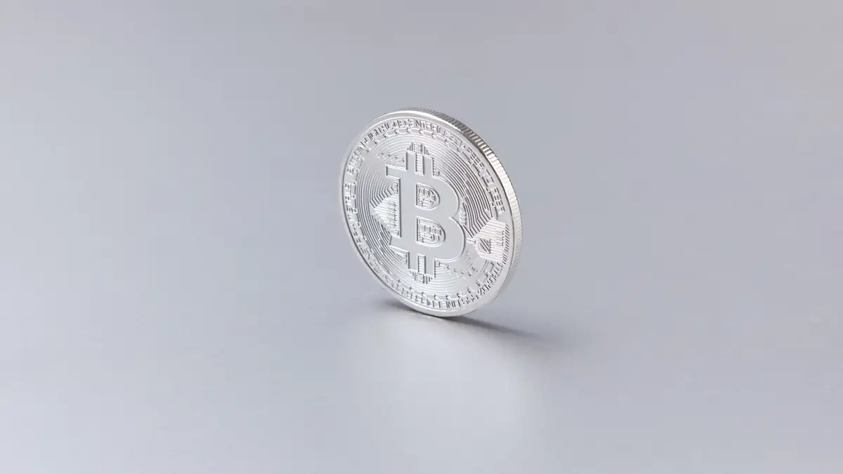 Moeda de Bitcoin prateada em pé sobre fundo branco