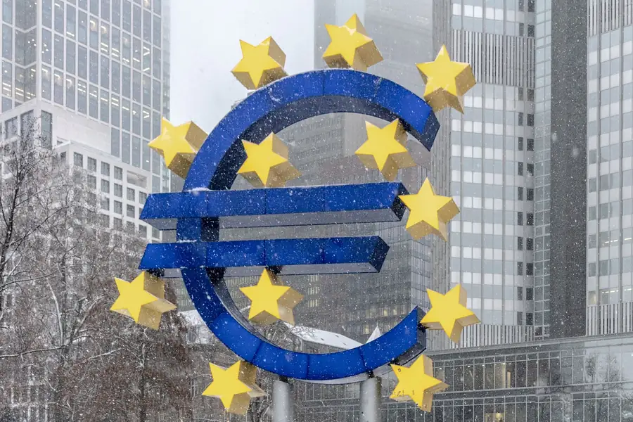 Escultura do símbolo do euro em frente a arranha-céus em Frankfurt, na neve
