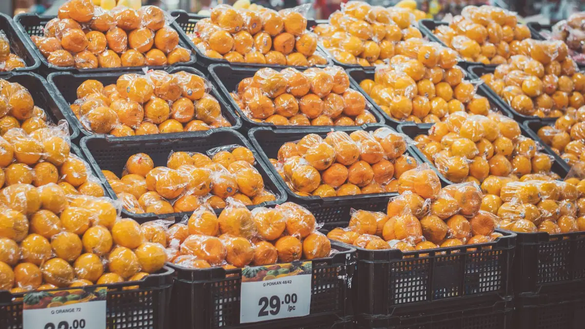 Pilha de laranjas embaladas em plástico com etiquetas de preço em um mercado