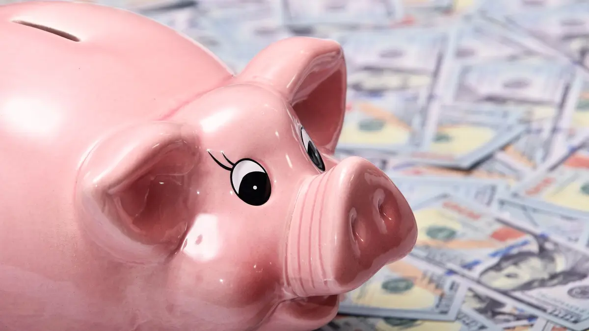 Cofrinho cor-de-rosa sobre notas de dólar