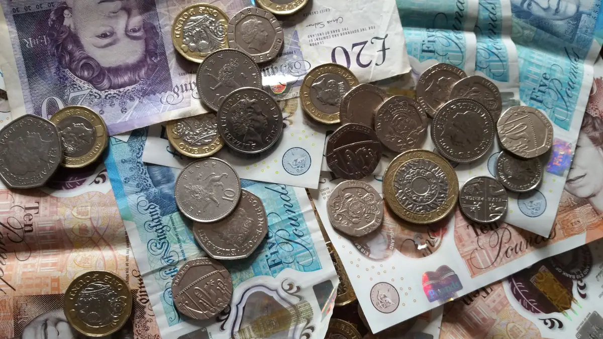 Moedas e notas de libra esterlina sobre uma mesa