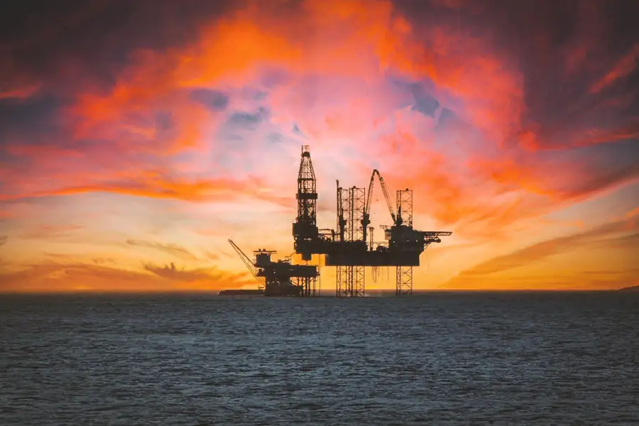 Plataforma de petróleo em silhueta contra um pôr do sol Plataforma de petróleo em silhueta contra um pôr do sol