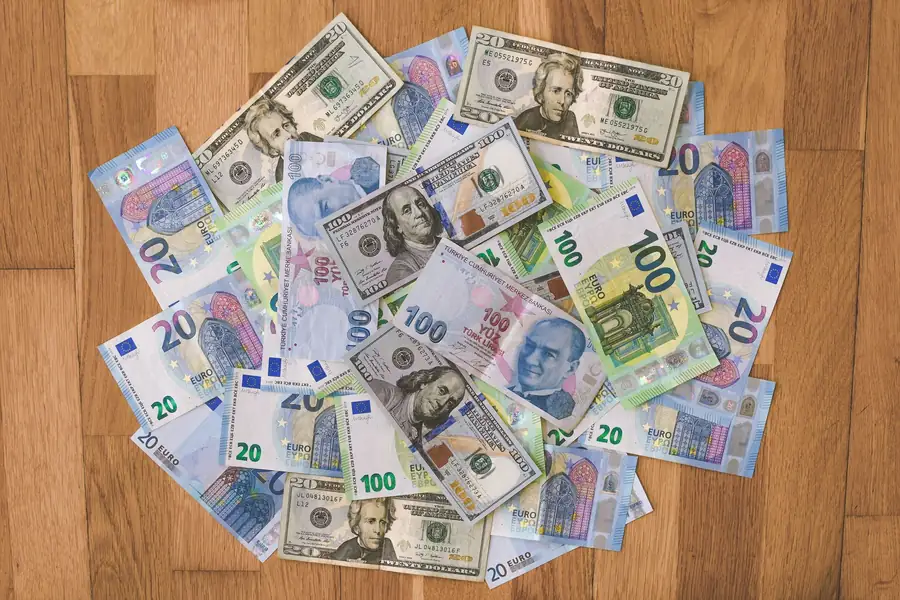 Notas de dólar, euro e lira turca dispostas sobre uma mesa de madeira