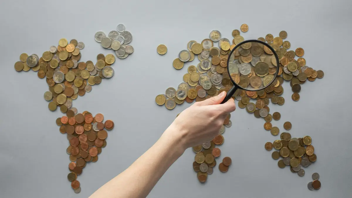 Moedas formando um mapa-múndi observadas com uma lupa