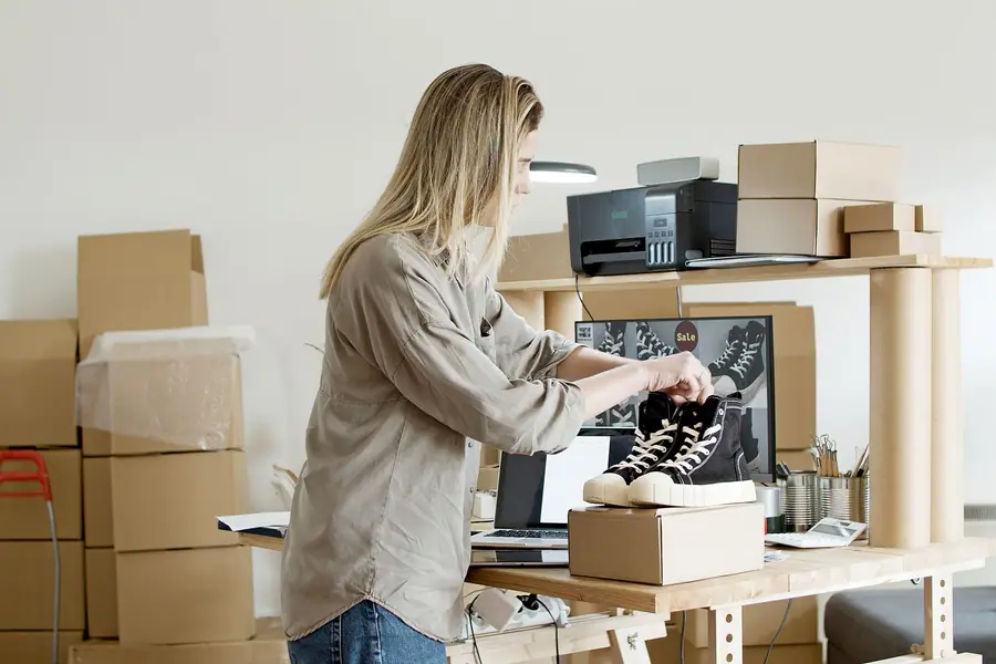 Mulher embalando tênis em uma caixa no seu espaço de trabalho de e-commerce