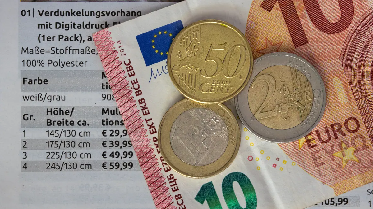 Notas e moedas de euro sobre uma lista de preços