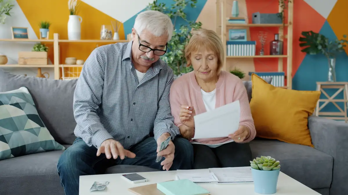 Casal de idosos planejando o orçamento e revisando documentos na sala de casa