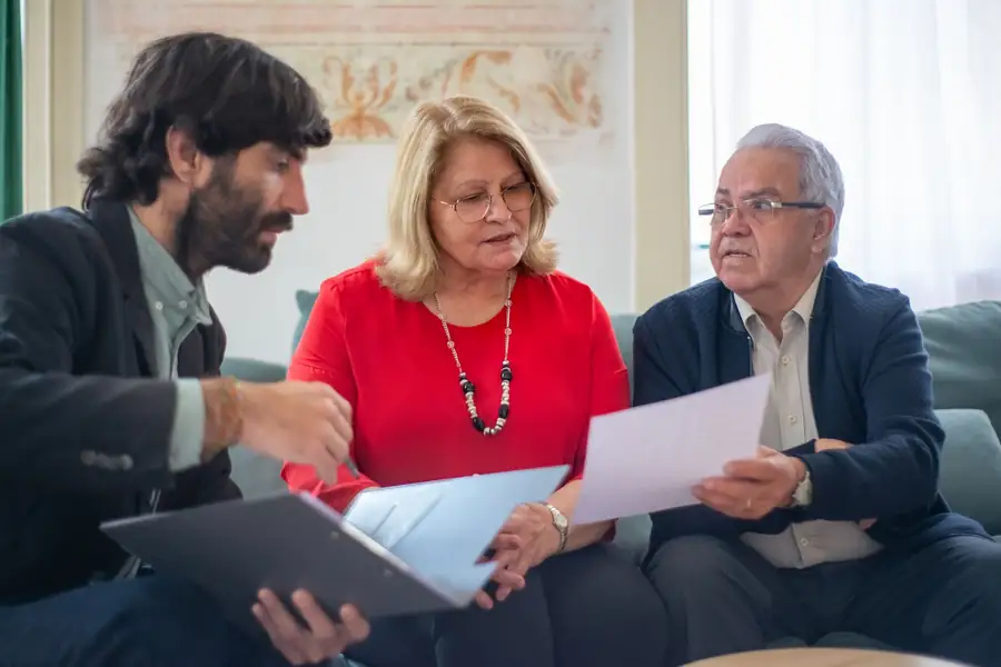 Casal de idosos conversando com um consultor financeiro sobre documentos em uma mesa