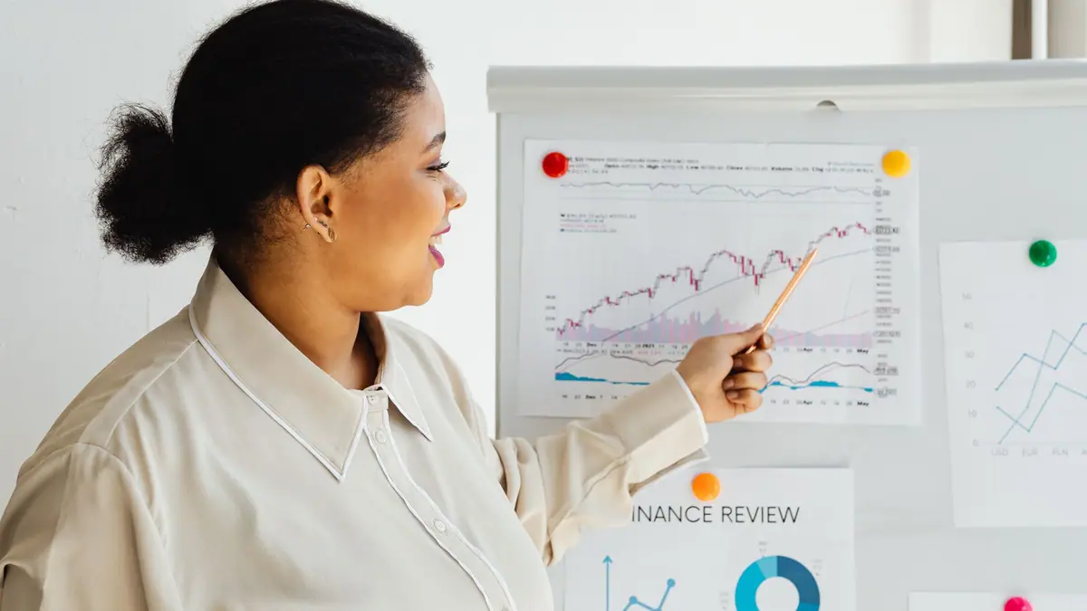 Mulher apontando para um gráfico do mercado de ações em um quadro branco