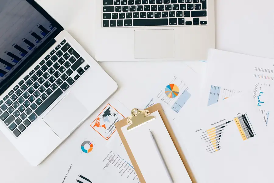 Documentos financeiros e notebook com gráficos de câmbio Documentos financeiros e notebook com gráficos de câmbio