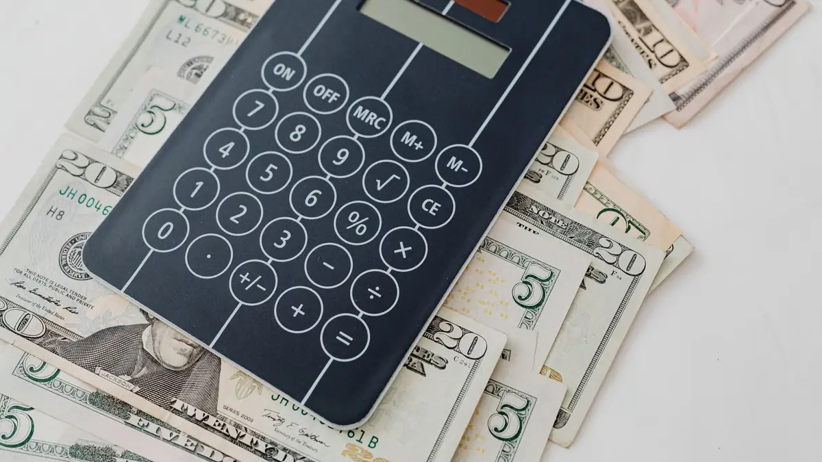 Notas de dólar e calculadora sobre uma mesa