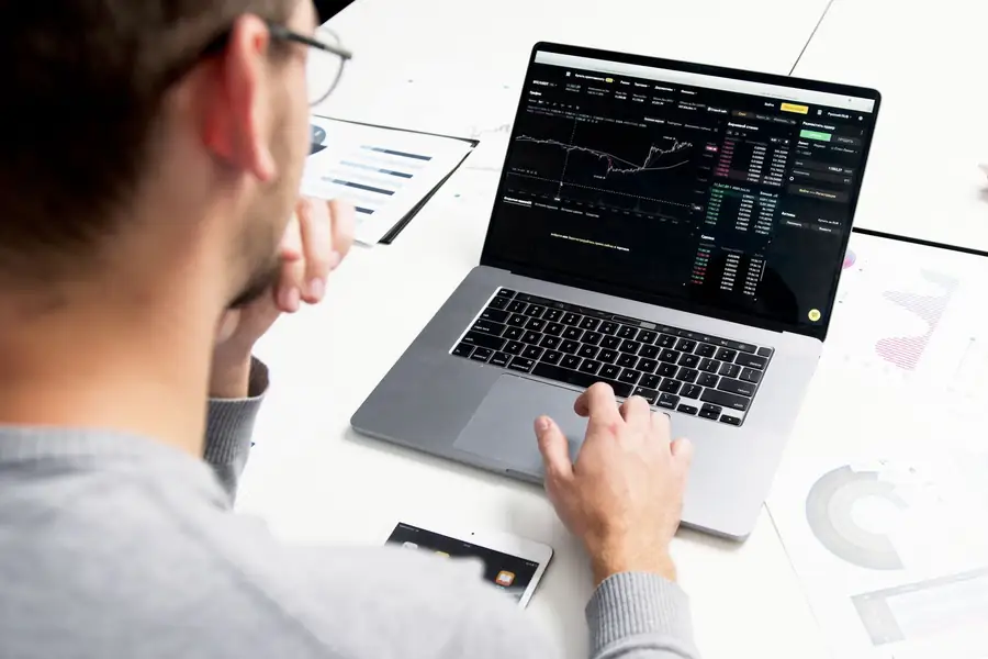 Pessoa analisando gráficos de investimento em um notebook