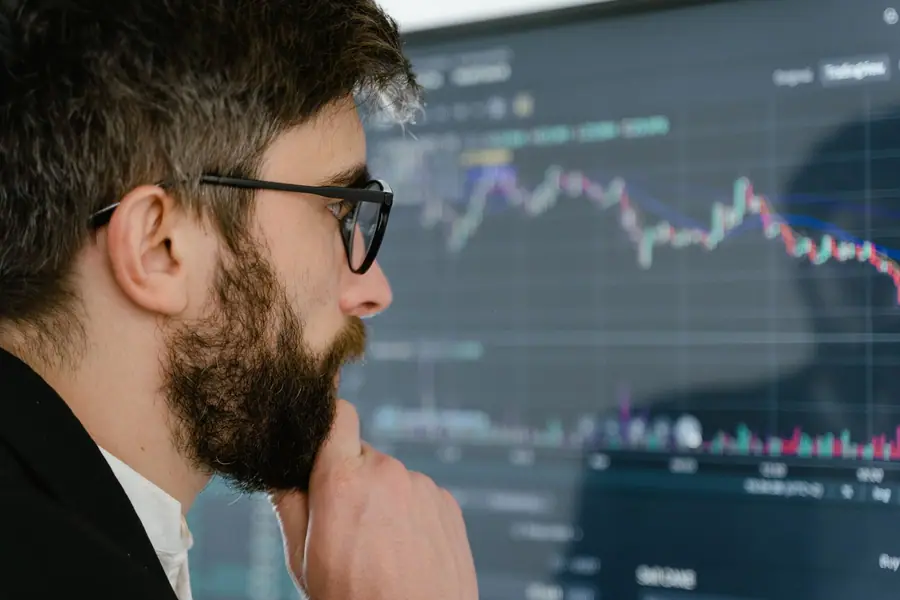 Homem concentrado estudando gráficos do mercado em uma tela
