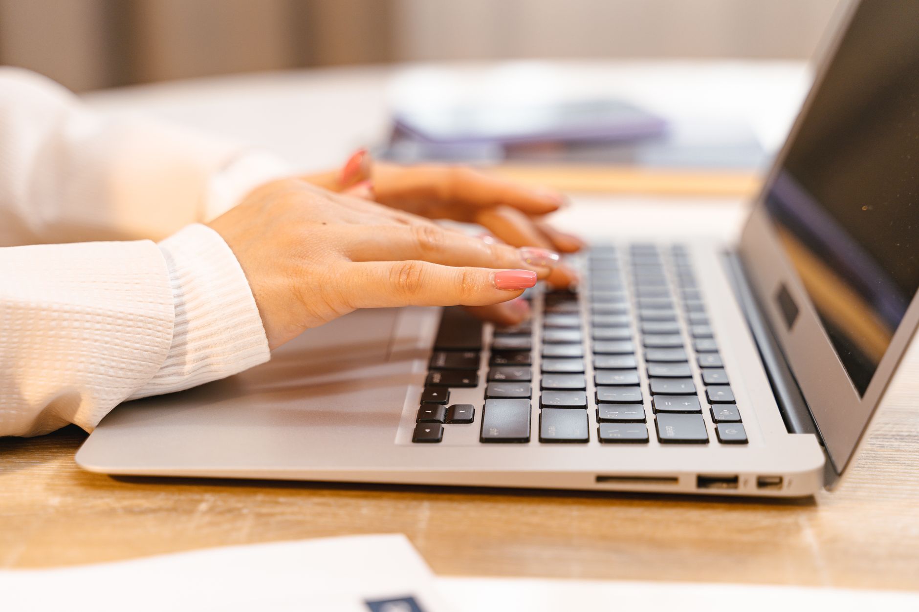 Profissional trabalhando com notebook em uma mesa de home office enquanto participa de uma reunião virtual