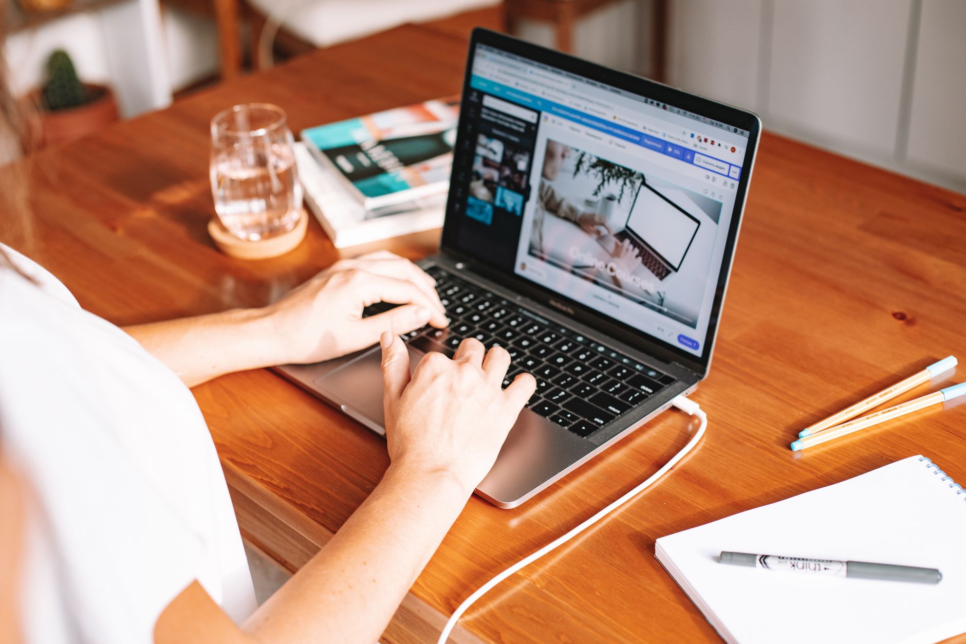 Pessoa trabalhando com notebook em uma estação simples e organizada dentro de casa.