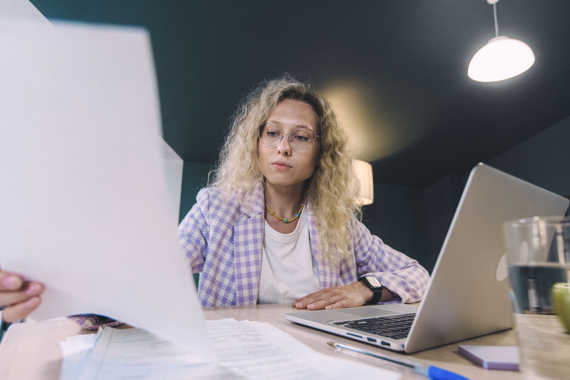 Freelancer conferindo documentos e notebook em uma mesa de trabalho