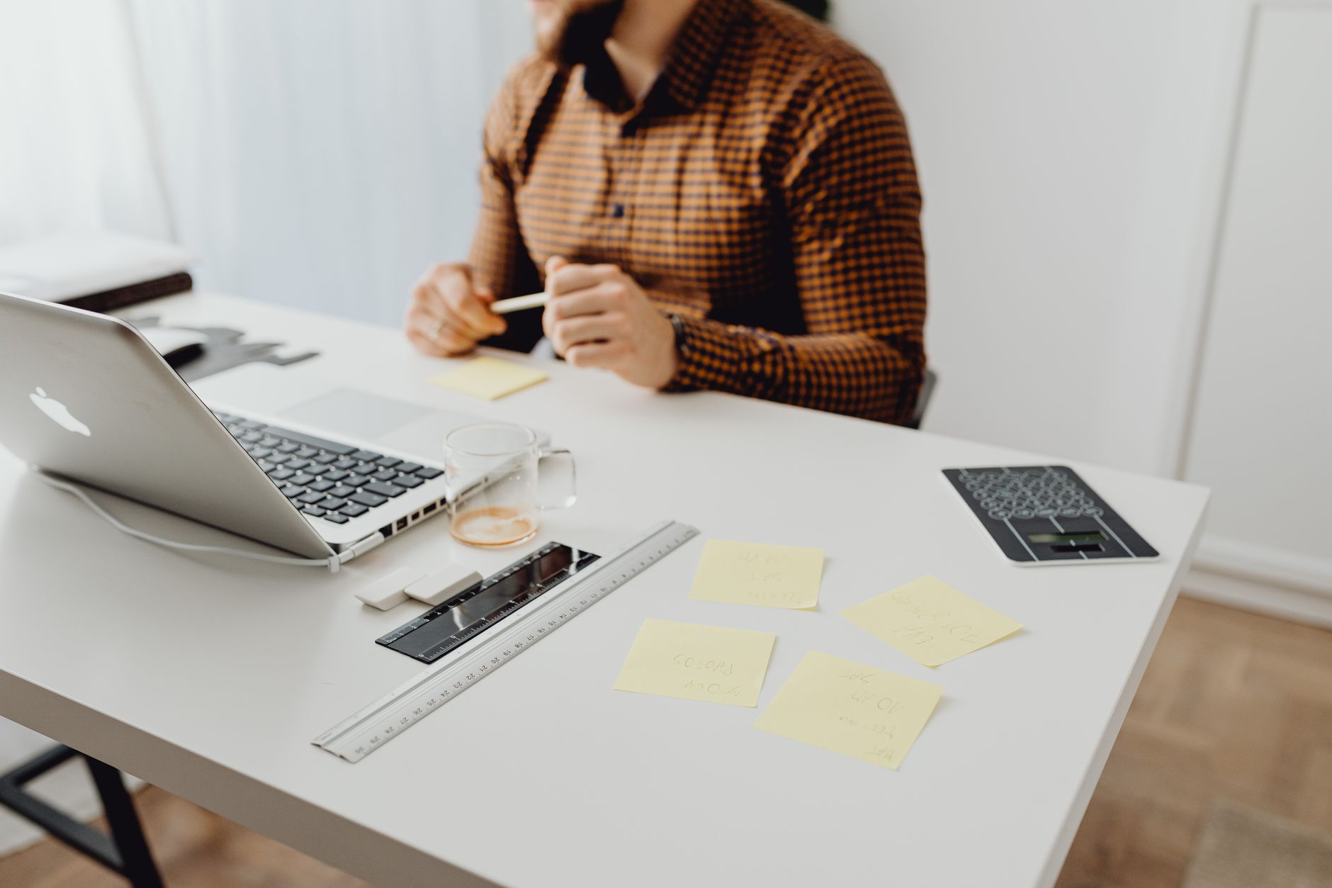 Pessoa trabalhando em casa com notebook protegido em uma mesa organizada