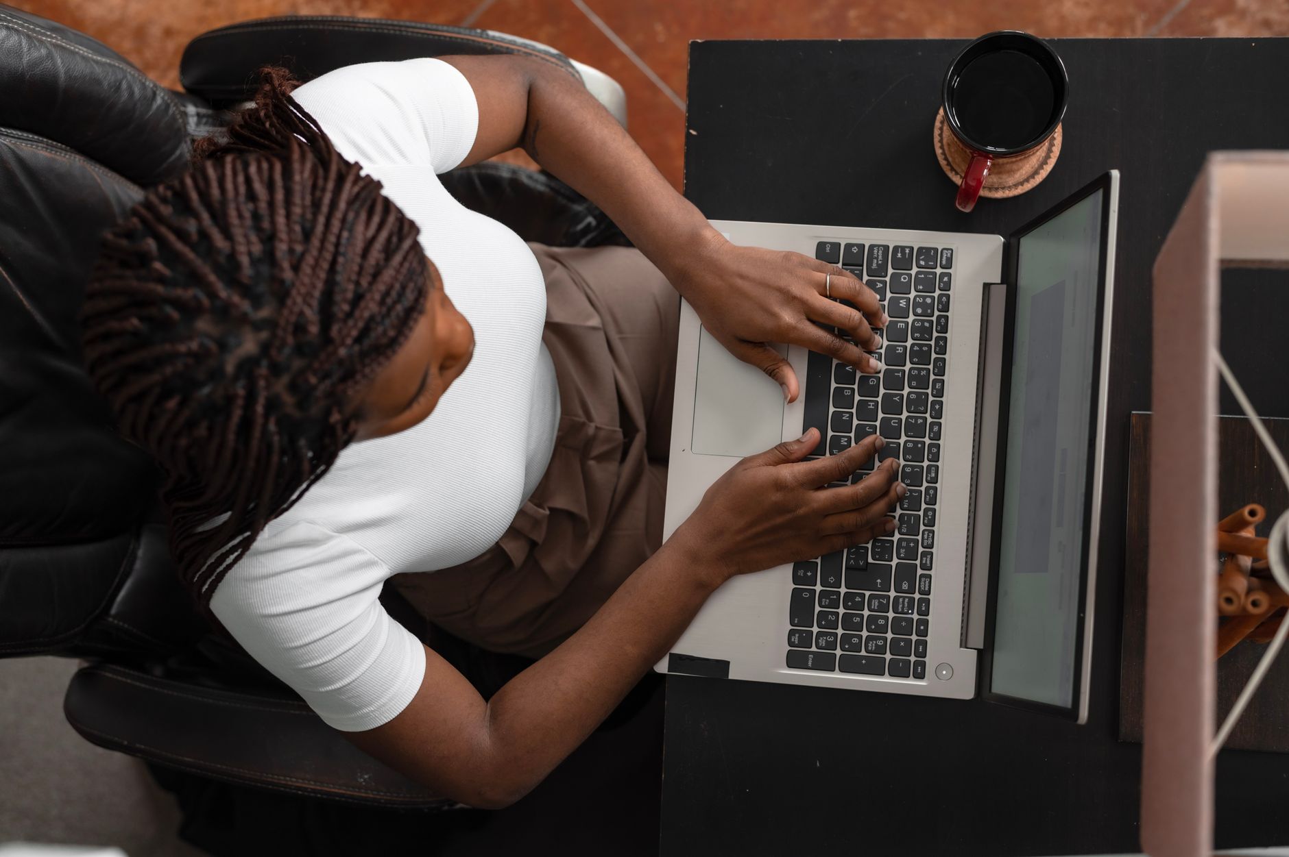 Pessoa trabalhando com digitação em um notebook sobre uma mesa de home office