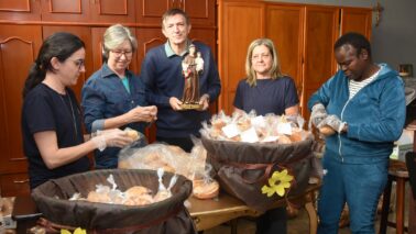 DEVOÇÃO: Padre Deonísio junto das voluntárias que embalam os pães para distribuição Paróquia distribui 3 mil pães no dia de Santo Antônio