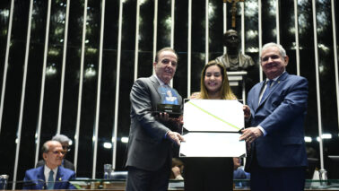 Henrique recebeu a comenda de Liana Andrade (representante do presidente do Senado) e do senador Angelo Coronel (Foto: Saulo Cruz/Agência Senado)