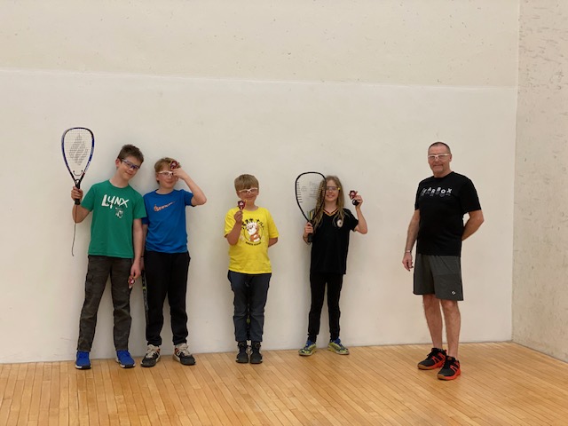 Four male youth and one female youth holding Racquetball Canada Badge Program Badges with their coach. 