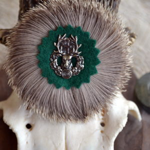 Round hat pin with badger hair wreath and cast metal deer motif at centre.