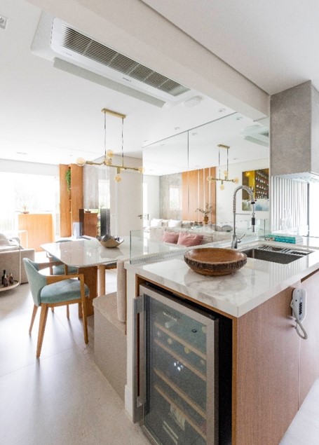 Adega na cozinha? Pode sim! Na execução deste apartamento, a formatação idealizada pela arquiteta Daniela Funari fez todo sentido: na bancada onde está localizada a pia e que está interligada com a sala de jantar, ela lançou mão da marcenaria sob medida para incluir o aparelho com total discrição e praticidade | FOTO: Mariana Camargo