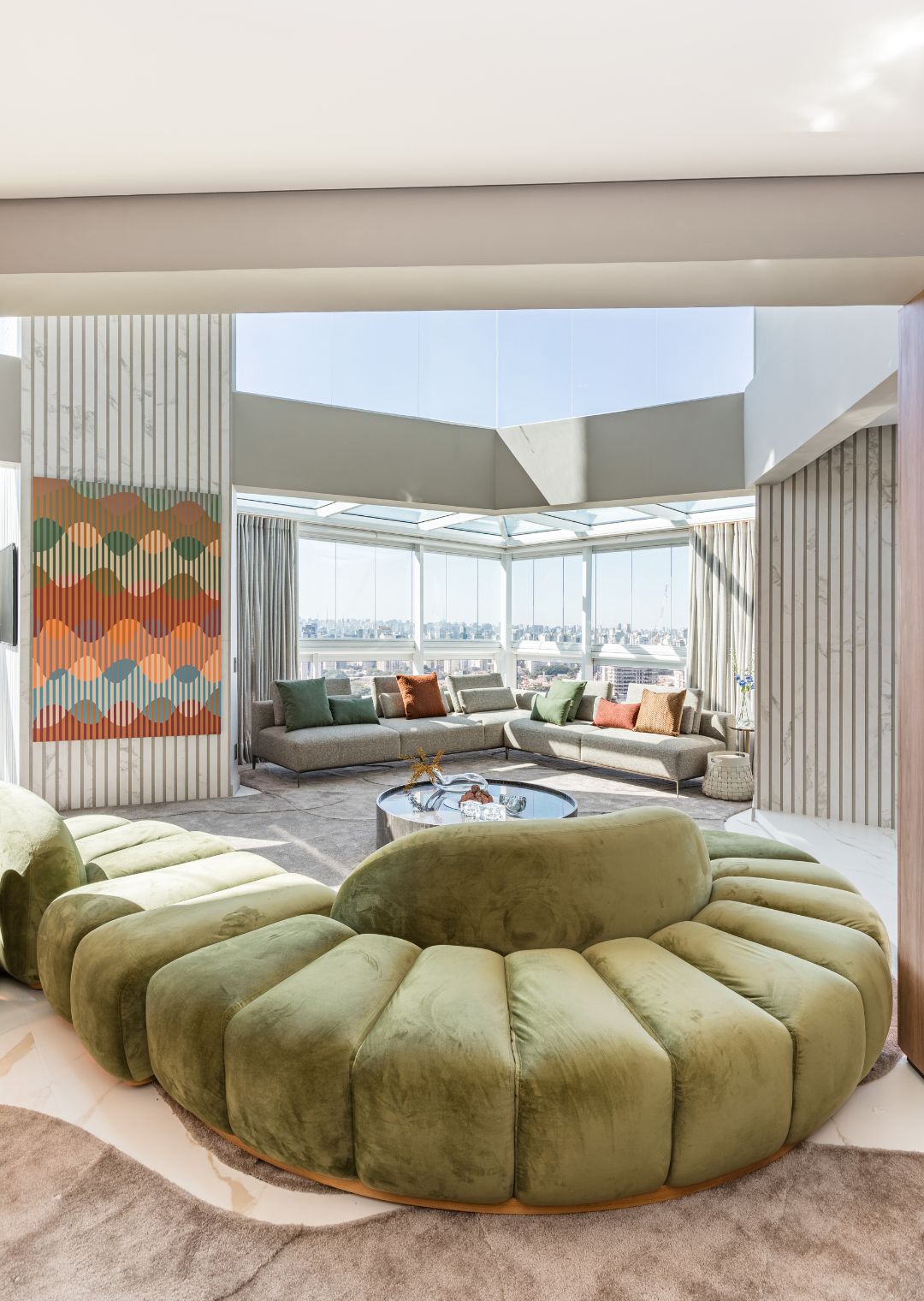 Um dos pontos altos do projeto assinado pela arquiteta Ana Rozenblit é o sofá orgânico que se adapta ao ambiente e abraça os pilares do meio da sala | Projeto Spaço Interior | Foto: Kadu Lopes